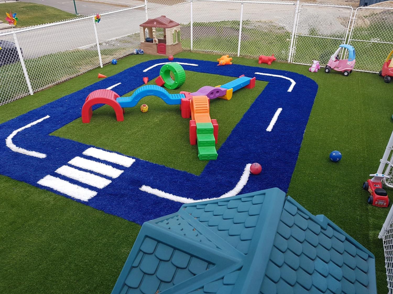 “Children’s daycare playground with colorful artificial turf, interactive play structures, toy race track design, and safe outdoor activity area