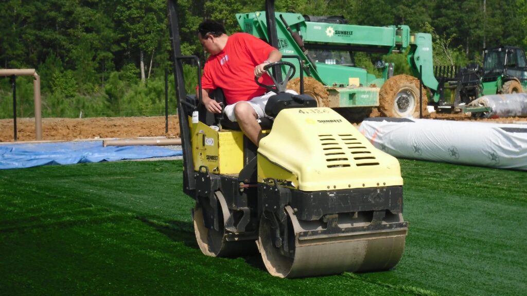 GTR Turf crew compacting synthetic field base during artificial grass sports field installation process.