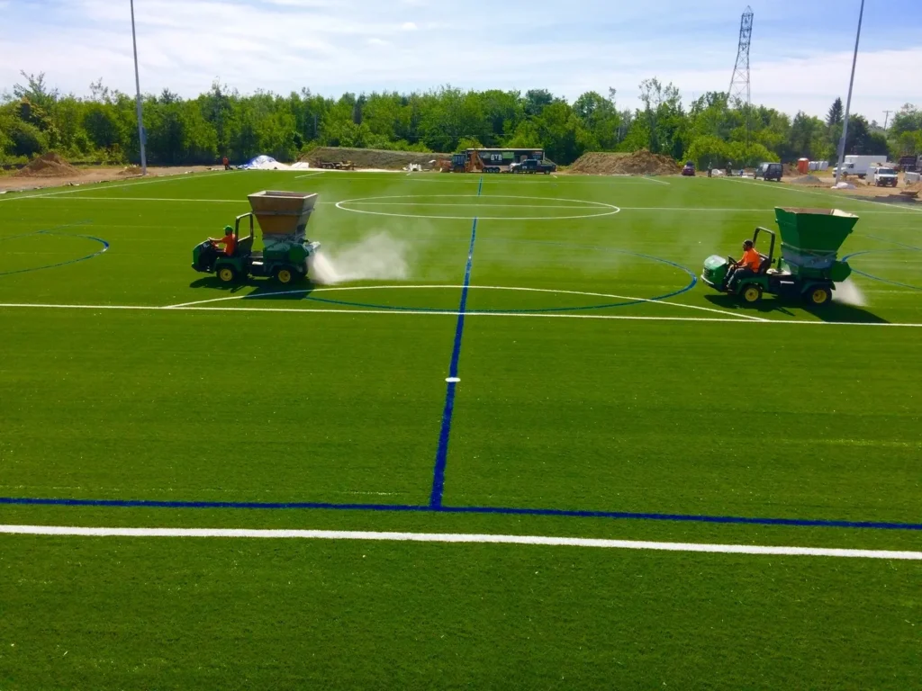 GTR Turf crew applying infill on synthetic sports field during professional artificial grass installation project.